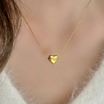 Close-up of a gold-tone heart pendant necklace without engraving worn over a white knit
