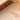 Gold-tone four-leaf clover necklace on a peach surface beside a wooden shelf